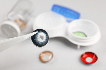 Tweezers with blue contact lens over table, closeup. Space for text