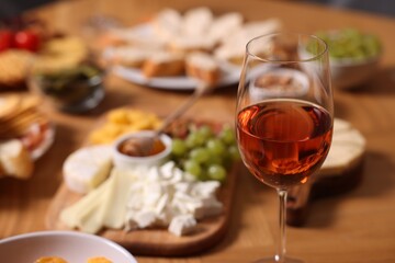 Glass of rose wine and appetizers served on wooden table, selective focus. Space for text