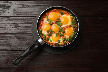 Delicious shakshuka in frying pan on wooden table, top view