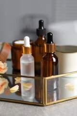 Bottles of cosmetic serum and beauty products on gray table, closeup