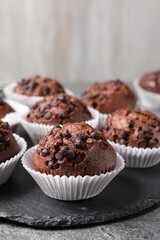 Tasty chocolate muffins on grey textured table, closeup. Space for text