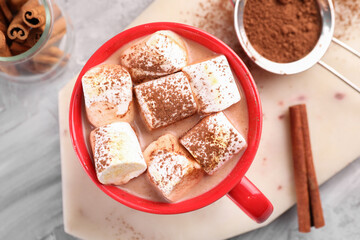 Cup of aromatic hot chocolate with marshmallows, cocoa powder and cinnamon sticks on table, top view