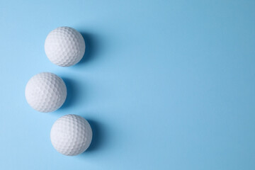 Three golf balls on light blue background, flat lay. Space for text