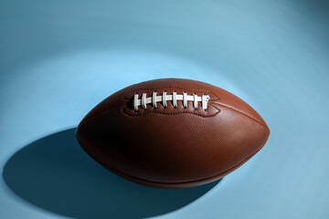 American football ball on light blue background