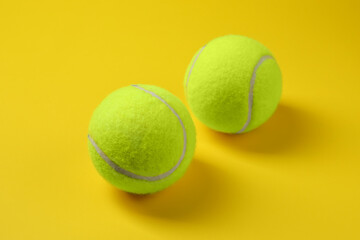 Two bright tennis balls on yellow background