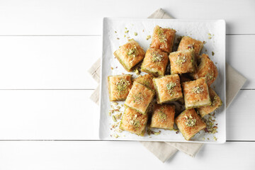 Delicious fresh baklava with chopped nuts on white wooden table, top view and space for text. Eastern sweets