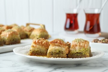 Delicious fresh baklava with chopped nuts on white marble table, closeup. Eastern sweets