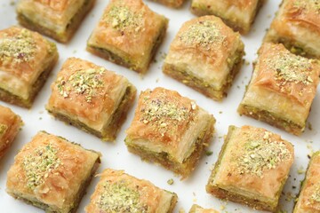Delicious fresh baklava with chopped nuts on white table, closeup. Eastern sweets