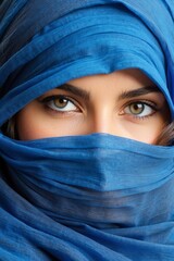Naklejka premium Close-up portrait of a beautiful Arab Muslim woman wearing a blue hijab. Only the eyes and direct gaze into the camera are visible.