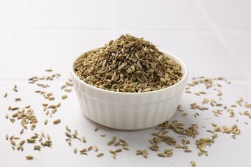Bowl with fennel seeds on white table, closeup