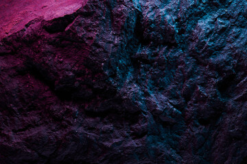Black stone texture in pink blue neon lighting, dark abstract background. Natural mineral rock close up details, empty backdrop with copy space for design