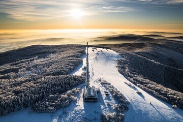 Aerial view of transmitter, cell tower surrounded by a forest during winter. Drone view of snowy...