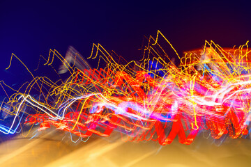 Blurred moving red, yellow and white lights on a german Autobahn seen through the windshield while...
