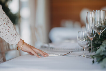 Woman preparing romantic table setting for indoor wedding reception. Luxury wedding table...
