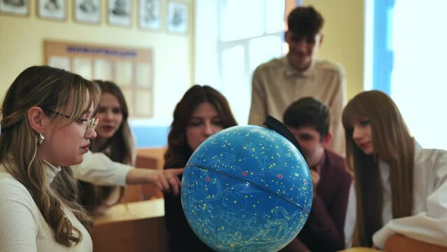 Students look at a globe of the starry sky in a classroom at school.