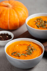 Pumpkin soup with seeds, spices, pepper on a gray background close up. The concept of healthy vegetable soups. Concept vegetarian food. Healthy seasonal autumn cuisine