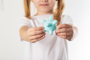 A blonde girl holds a model of a virus in her hands. Concept of infectious diseases in children,...