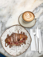 top view delicious croissant with strawberry fruit and chocolate by cup of cappuccino