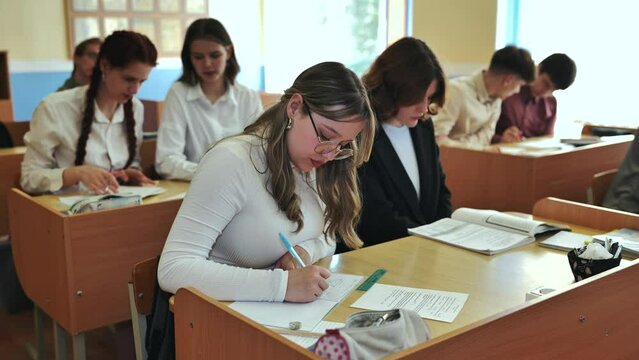 Girl students writing math formulas in a notebook.