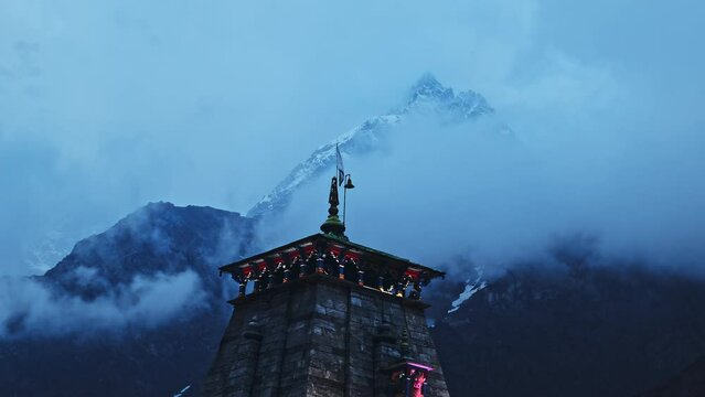A beautiful shot of the cloudy and snowy Himalayan mountains behind the Kedarnath temple in Uttarakhand, India.