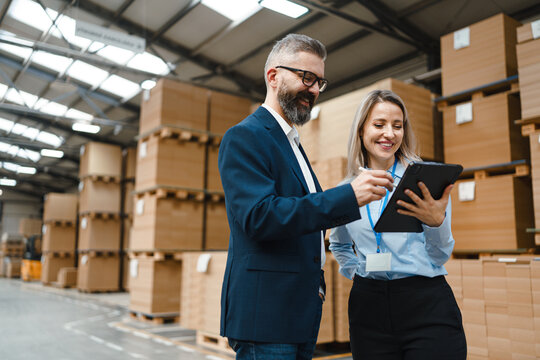 Female warehouse manager talking with logistics employee in warehouse, planning transport of products, goods, talking shipping process. - Powered by Adobe