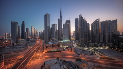 Fototapeta premium Aerial view of Dubai Downtown skyline with many towers night to day timelapse.