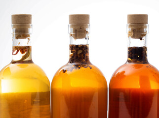 Transparent bottles with brown alcoholic drink on a white background. The concept of homemade herbal tinctures from moonshine. Homemade cognac and brandy.