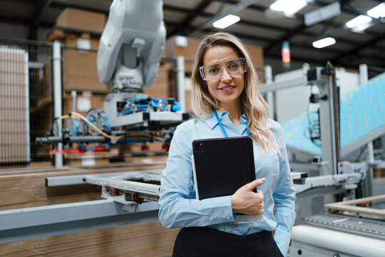 Female manager standing in modern industrial factory. Manufacturing facility with robotics and automation. Female leader, CEO in heavy industry, manufactury.