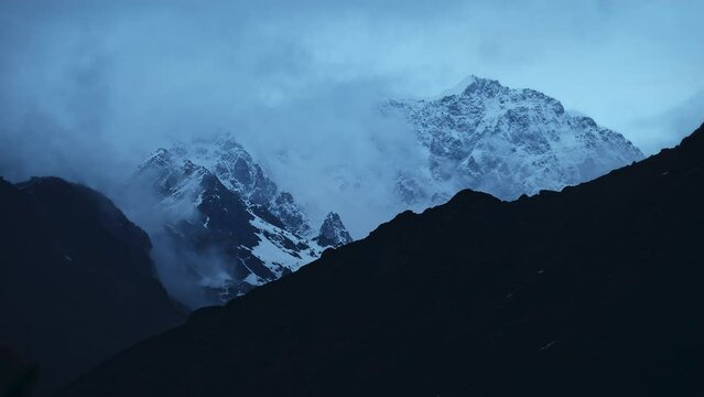 A beautiful timelapse shot of the cloudy and snowy Himalayan mountains behind the Kedarnath temple in Uttarakhand, India.
