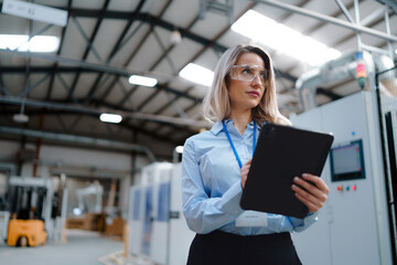 Female manager standing in modern industrial factory. Manufacturing facility with robotics and automation. Female leader, CEO in heavy industry, manufactury.