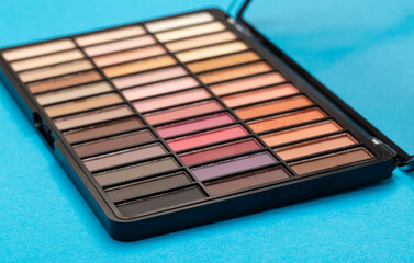 A set of modern eye shadows with powdery shades on a blue background. Soft texture and shading, brand.