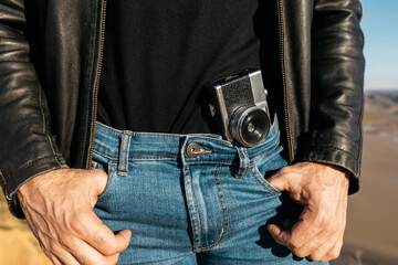 Vintage camera tucked in man's jeans with leather jacket