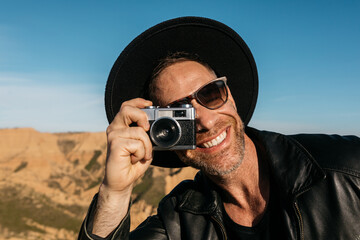 Smiling photographer capturing the moment outdoors with a film camera