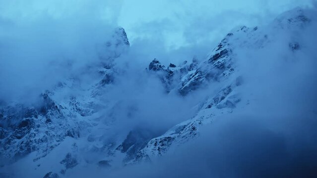 A beautiful timelapse shot of the cloudy and snowy Himalayan mountains behind the Kedarnath temple in Uttarakhand, India.