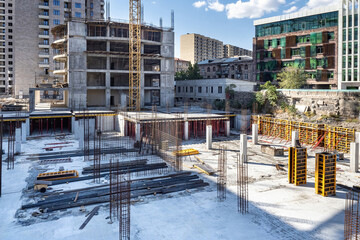 Construction site. Erection of multi-storey block. Houses under construction under winter sky. Erection of high-rise residential buildings. Construction site is covered with snow. Architectural works
