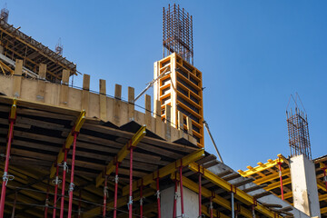 Construction industry. Building under construction with wooden formwork. Process of constructing residential area. Unfinished house under blue sky. Building under construction with temporary supports - obrazy, fototapety, plakaty