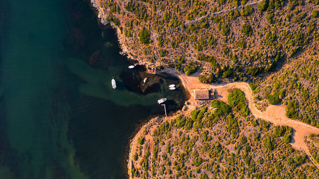 Aerial view of Sanitja natural port in Menorca with winding road along a rugged coastline