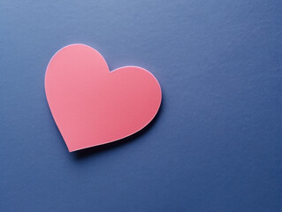 Fototapeta premium A single pink paper heart on a deep navy blue matte background.