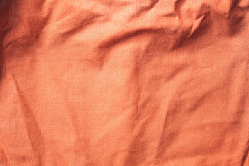 Texture of old crumpled textile material in peach fuzz color