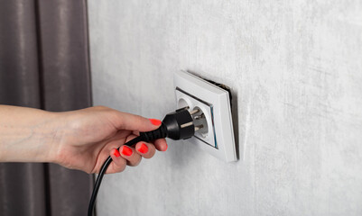 The girl removes the electrical plug from the socket and breaks the socket out of the socket....