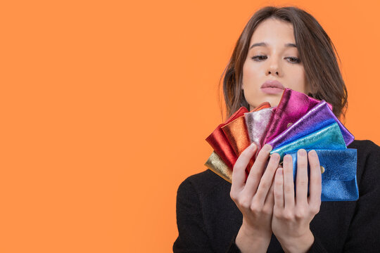 Young woman with colorful wallets isolated over orange background