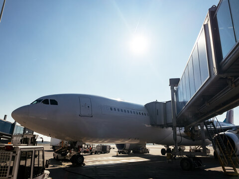 Airplane at airport gate under sunny sky