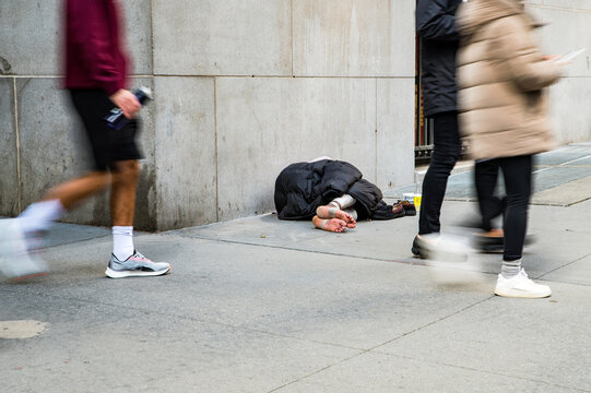 Unrecognizable homeless man lying on street