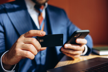 Business man holding credit card and shopping online on the phone