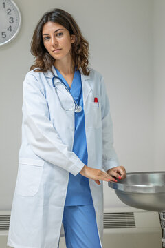 Young woman doctor in uniform standing near sink in clinic