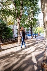 Fototapeta na wymiar Full length of blind woman with white cane crossing on the road in the city