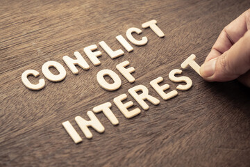 Closeup man arrange the small wooden letters on the table as Conflict of Interest concept - obrazy, fototapety, plakaty