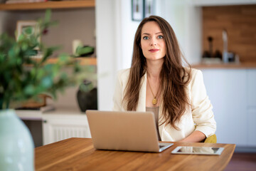 Brunette haired woman sitting at home and using laptop