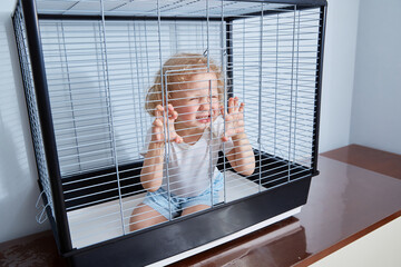 A frustrated child is sitting in a cage. The topic is bullying of children.