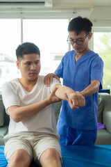 Obraz premium Physiotherapy doctor treating patient whose arm is recovering, doing physical therapy to stretch muscles in clinic
